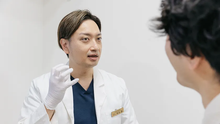 明るい診察室で、医師と患者さんが真剣に話をしています。信頼関係を感じさせる光景です。