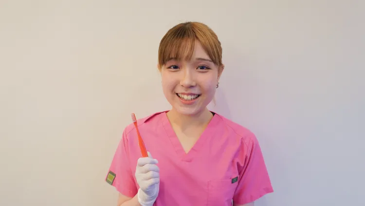 明るく笑顔の歯科衛生士さんが、歯ブラシを手にしています。