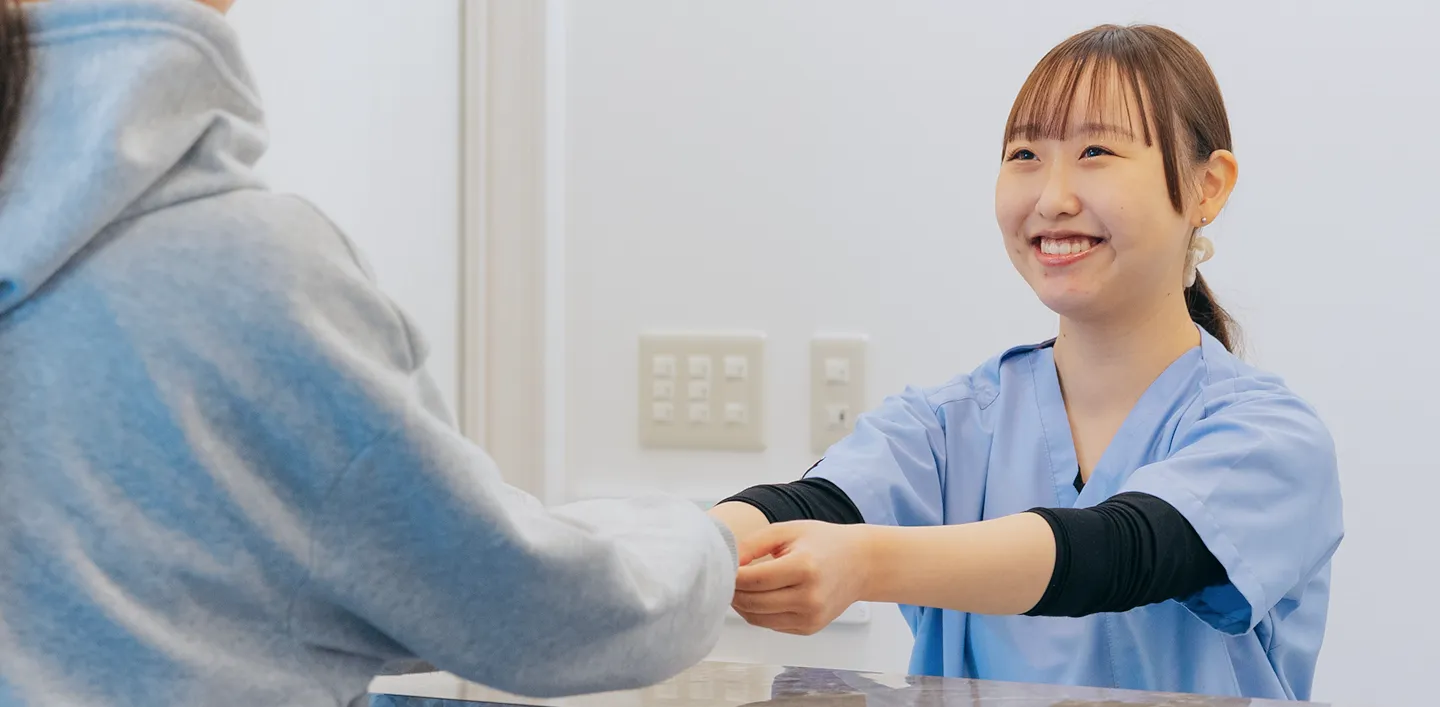 明るい笑顔と優しい手つきで、患者さんと接する医療従事者。