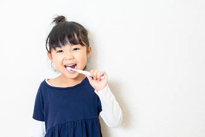 小さな女の子が笑顔で歯みがきをしている様子。楽しそうに歯みがき習慣を実践している。