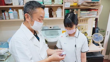 研修中の学生とベテラン医師。真剣な眼差しで、精密な作業に取り組んでいます。