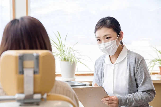 歯科医院でマスクを着けたスタッフが食生活の指導をしている様子。